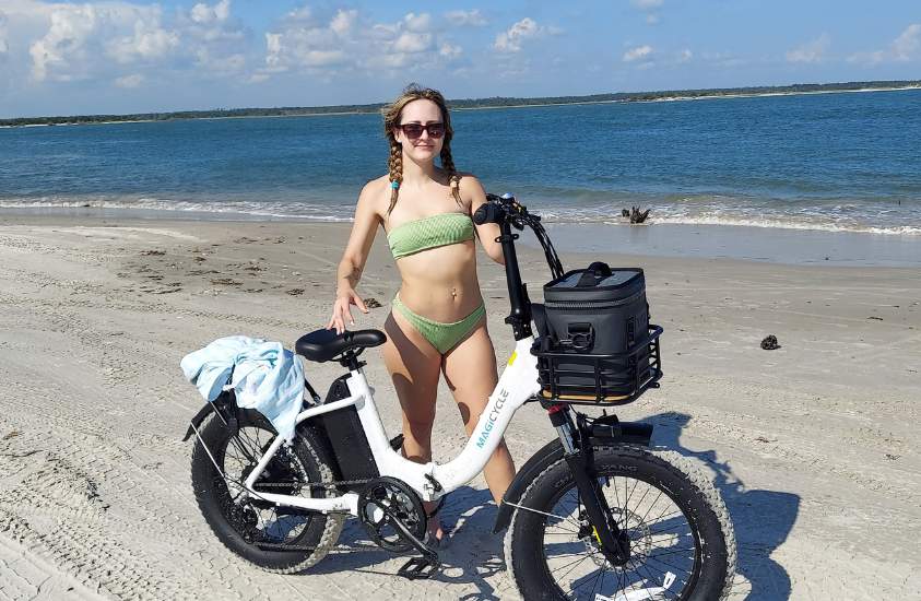 Kassidy standing by the Magicycle fat tire electric bike at the beach
